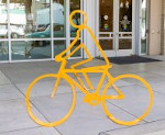 Three yellow bike racks that line up to form a person on a bike
